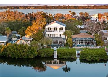 Waterfront home showcasing its multi-level balconies, private dock, lush landscaping, and serene water views at 8258 Midnight Pass Rd, Sarasota, FL 34242