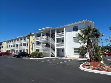 Bright white condo building with outdoor stairs, parking, and landscaping under a clear blue sky at 1633 Leisure Dr # M-37, Bradenton, FL 34207