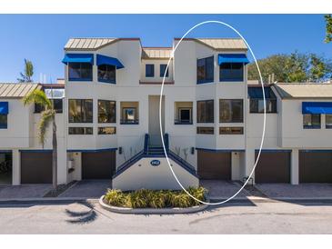 Condo building with private garages, lush landscaping, and vibrant blue accents at 1912 Harbourside Dr # 602, Longboat Key, FL 34228