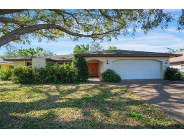 Charming single-story home featuring a two-car garage and a well-manicured front yard with mature trees and lush landscaping at 3640 Aster Dr, Sarasota, FL 34233