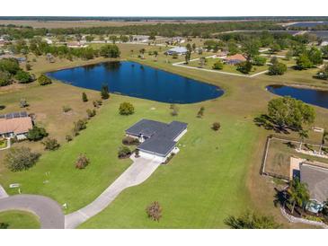 Expansive aerial view of single-story home featuring a private pond, lush green lawn, and long concrete driveway at 4606 Lake Fox Pl, Parrish, FL 34219