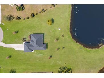 An aerial view shows this home's placement on a grassy lawn next to a dark lake with a winding driveway at 4606 Lake Fox Pl, Parrish, FL 34219