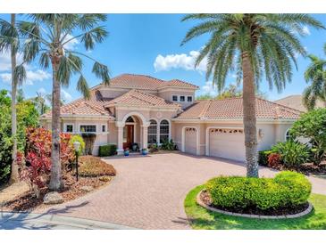 Elegant Mediterranean-style home featuring a tile roof, paver driveway, and lush tropical landscaping at 13708 Red Rock Pl, Lakewood Ranch, FL 34202