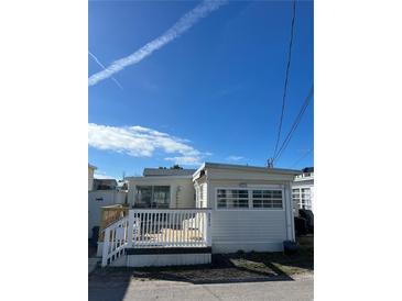 Charming exterior view of home featuring a quaint deck and light siding under a bright blue sky at 2601 Gulf N Dr # 221, Bradenton Beach, FL 34217