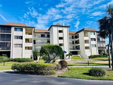 Multi-story condo building featuring lush landscaping, balconies, and a bright blue sky at 3630 Gulf Of Mexico Dr # 304, Longboat Key, FL 34228