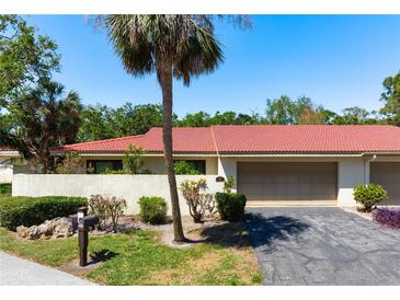 Charming single-story home with a red tile roof, lush landscaping, and an attached two-car garage at 3804 Sun Eagle Ln, Bradenton, FL 34210
