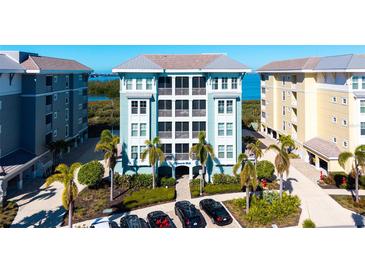 Beautiful coastal condo building featuring tropical landscaping, covered parking, and a water view at 388 Aruba Cir # 201, Bradenton, FL 34209