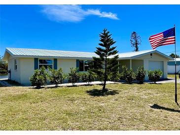 Charming single-story home with a metal roof, manicured landscaping, and American flag at 41 Young Ave, Englewood, FL 34223