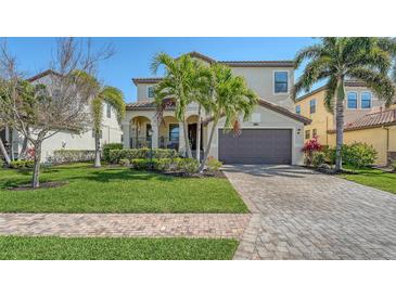 Charming two-story home with well-manicured lawn, lush landscaping, and a brick-paved driveway at 5723 Title Row Dr, Bradenton, FL 34210