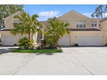 Light yellow townhome with attached garages, palm trees, and small landscaped garden at 6412 Rosefinch Ct # 102, Lakewood Ranch, FL 34202