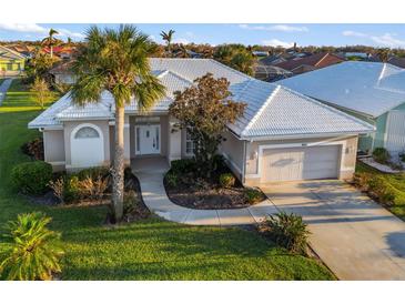 Charming home exterior boasts a lush lawn, beautiful landscaping, and a white tile roof at 664 Silk Oak Dr, Venice, FL 34293