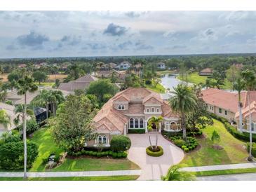 Expansive home features a tiled roof, manicured landscaping, and a circular driveway with palm tree centerpiece at 6822 Dominion Ln, Lakewood Ranch, FL 34202