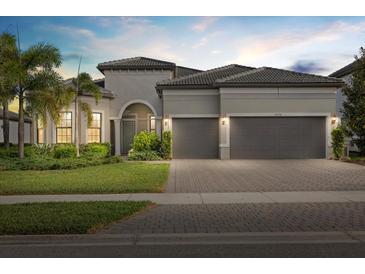 Charming single-story home with a tile roof, arched entry, three-car garage and well-manicured landscaping at 8016 Grande Shores Dr, Sarasota, FL 34240