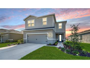Charming two-story home with landscaped yard, gray siding, and a two-car garage at sunset at 8918 Waxwing Way, Parrish, FL 34219