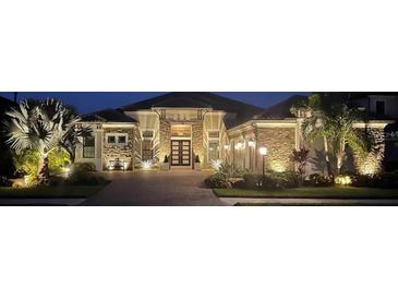 Exterior night shot of home featuring stone facade and manicured landscaping with accent lighting at 5313 Greenbrook Dr, Sarasota, FL 34238