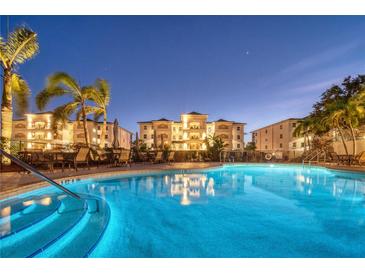 Beautifully lit outdoor pool with lounge chairs, palm trees, and condo buildings at night at 9203 Griggs Rd # B102, Englewood, FL 34224