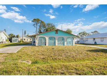 View of the home's arched entry showing the front exterior with large yard and driveway at 270 E Langsner St, Englewood, FL 34223
