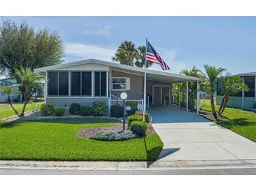 Charming home featuring a screened-in porch, covered parking, and an American flag waving proudly at 8402 Princess Ct, Palmetto, FL 34221