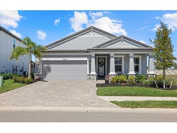 Beautiful single-story home with a brick paved driveway, grey exterior and well-manicured landscaping at 17676 Savory Mist Cir, Bradenton, FL 34211