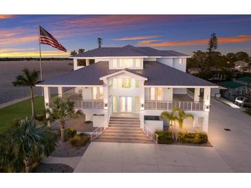 Stunning waterfront home featuring multiple balconies, a metal roof, and ample parking, all set against a colorful sunset at 327 Riverpoint Ne Dr, Bradenton, FL 34208