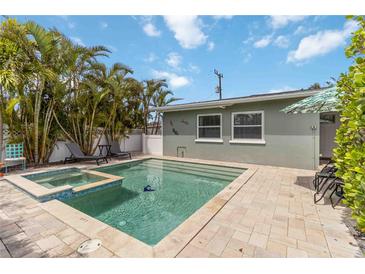 Beautiful in-ground pool and jacuzzi are surrounded by palm trees and patio with lounge chairs at 424 62Nd St, Holmes Beach, FL 34217
