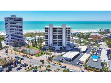 Stunning aerial view of the condo building, beach, and tennis courts on a sunny day at 5300 Ocean Blvd # 202, Sarasota, FL 34242