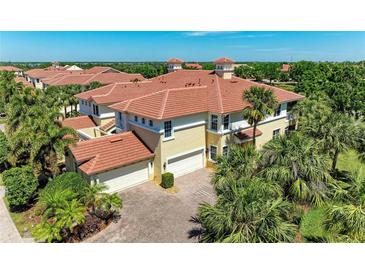 Expansive Mediterranean-style home with a red tile roof and attached two-car garage, surrounded by lush landscaping at 9429 Discovery Ter # 102B, Bradenton, FL 34212