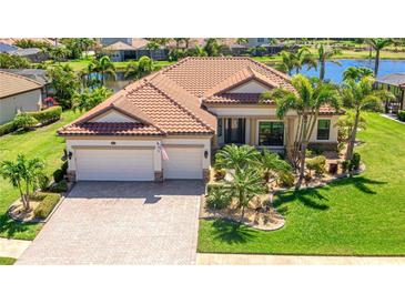 Beautiful waterfront home featuring a lush green lawn and meticulous landscaping at 20114 Uffizi Ct, Venice, FL 34293