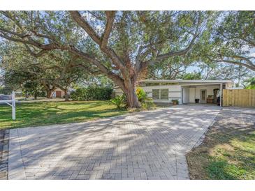 Charming single-story home featuring a beautifully landscaped front yard with mature trees and a brick-paved driveway at 3526 Austin St, Sarasota, FL 34231