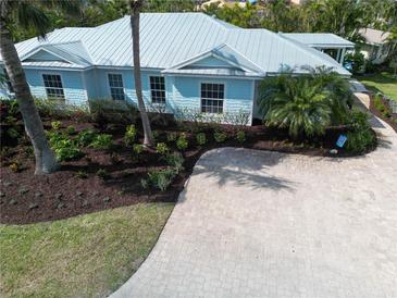 Stunning coastal home with lush landscaping, beautiful paver driveway, and a stylish light blue exterior at 5608 Holmes Blvd, Holmes Beach, FL 34217