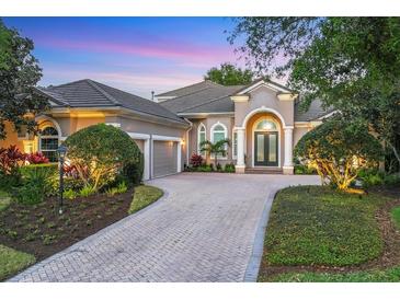 Stately home featuring manicured landscaping, a paver driveway and a grand double-door entrance with white columns at 7257 Greystone St, Lakewood Ranch, FL 34202