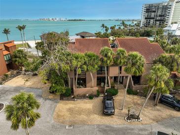 Coastal home with terracotta roof, palm trees, and gravel driveway, boasting views of ocean waters at 105 Pass Key Rd # 105, Sarasota, FL 34242