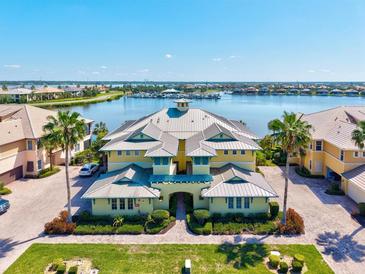 Waterfront condo building featuring a unique roofline with palm trees, landscaping, and a waterfront view at 1123 Riverscape St # D, Bradenton, FL 34208