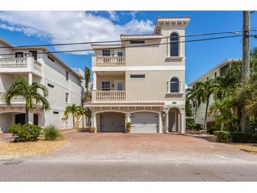 Three-story home featuring a two-car garage, balconies, a stucco exterior, and a brick-paved driveway at 2309 Avenue C # 200, Bradenton Beach, FL 34217