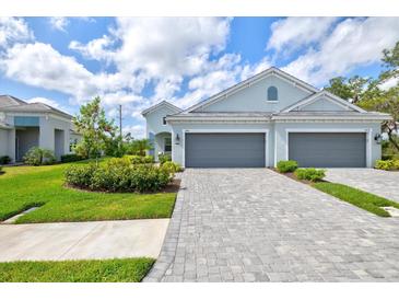 Charming single-Gathering home featuring a paver driveway, manicured lawn, and two-car garage at 2894 Butterfly Jasmine Trl, Sarasota, FL 34240