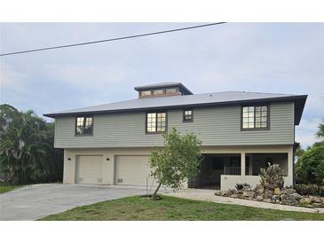 Two-story home featuring a light green exterior, multiple garage doors, and professionally landscaped yard at 33 Tee View Pl, Rotonda West, FL 33947