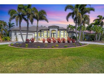 Stunning single-story home featuring a circular driveway, lush landscaping, and elegant architectural details at 435 La Sila Ct, Punta Gorda, FL 33950