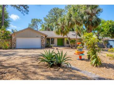 Charming single-story home featuring a well-manicured yard, stone accents and a bright green front door at 480 58Th St, Sarasota, FL 34243