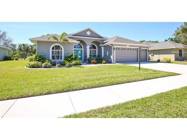 Charming home with arched windows, a bright blue door, and a well-manicured lawn at 8615 59Th E St, Parrish, FL 34219