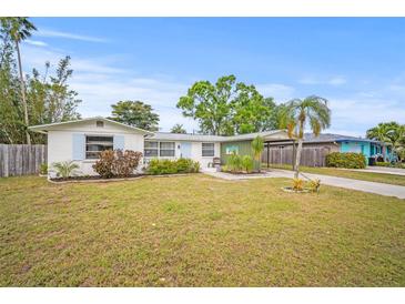 Charming single-story home with a well-maintained lawn, lush landscaping, and covered parking at 2620 White Sands Dr, Sarasota, FL 34231