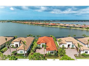 Stunning aerial view of waterfront homes with red tile roofs and lush landscaping overlooking a serene lake at 344 Maraviya Blvd, Nokomis, FL 34275