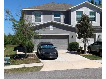 Charming two-story home featuring a gray exterior, well-maintained landscaping, and an attached two-car garage at 10668 Lake Montauk Dr, Riverview, FL 33578