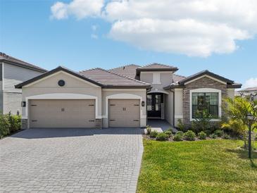 Beautiful single-story home featuring a three-car garage, well-manicured lawn, and stylish stone accents at 15104 Blue Bay Ter, Lakewood Ranch, FL 34211