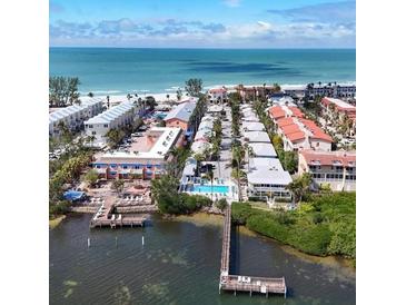 Stunning aerial view of waterfront property with private docks, pool, and beach access on a clear, sunny day at 1603 Gulf Dr N # 6, Bradenton Beach, FL 34217