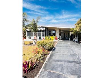Charming home exterior featuring a well-manicured lawn, mature trees, and a welcoming driveway at 1829 Cypress Point Ln, Sarasota, FL 34234