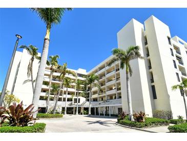Beautiful building exterior with bright white facade, lush tropical landscaping, and paved driveway at 1932 Harbourside Dr # 217, Longboat Key, FL 34228