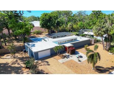 Modern home with a flat roof, solar panels, a front patio, and a well-manicured gravel yard at 448 58Th St, Sarasota, FL 34243