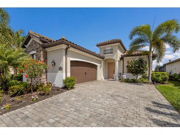 Charming single-Gathering home featuring a stone facade, a 2-car garage, and lush tropical landscaping at 5917 Cessna Run, Lakewood Ranch, FL 34211