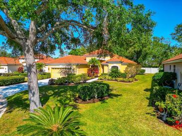 Charming single-story home featuring vibrant landscaping, a terracotta roof, and lush green lawn with mature trees at 7035 Owls Nest Ter, Bradenton, FL 34203