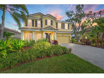 Two story home with yellow siding, brown shutters, manicured landscaping, and a paver driveway, perfect for curb appeal at 5522 Cartagena Dr, Sarasota, FL 34233
